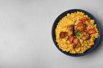 Bowl of delicious rice pilaf on grey background, top view with space for text