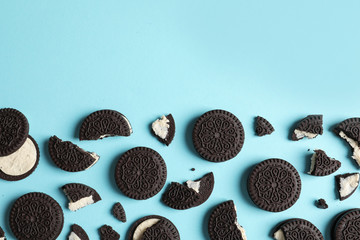 Tasty chocolate cookies with cream on color background, flat lay. Space for text