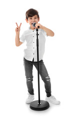 Cute little boy singing into microphone on white background