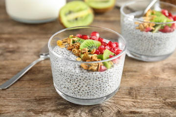 Dessert bowl of tasty chia seed pudding with granola, kiwi and pomegranate on table