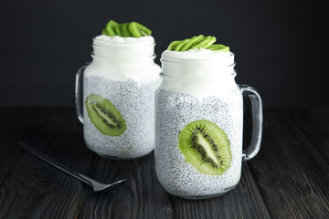 Mason jars of tasty chia seed pudding with kiwi on table