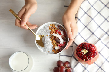 Young woman eating tasty chia seed pudding at table, top view