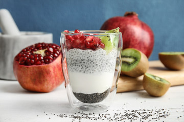 Glass of tasty chia seed pudding with kiwi and pomegranate on table