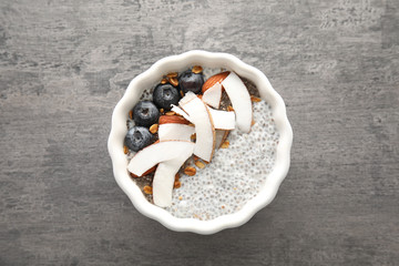 Bowl of tasty chia seed pudding with coconut, granola and blueberries on table, top view