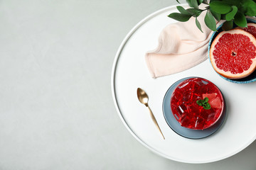 Flat lay composition with grapefruit jelly in bowl on light table. Space for text