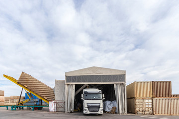 Contenedor descargando levantado sobre plataforma realizando operaciones de trasvase para cargar...
