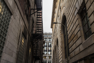 Fire escape stairs and ladder, in metal, on a typical North American old brick building from the Old Montreal, Quebec, Canada. These stairs, made for emergency, are symbolic of the architecture