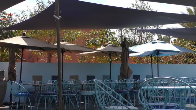 View of empty seats under parasols at tropical tourist resort outdoor cafe