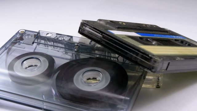 Three Vintage Audio Cassettes Rotate on White Background