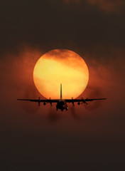 Portrait of transport aircraft in front of big sun in background