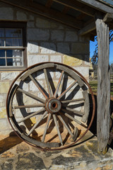 Antique wagon wheel leaning on an old western house.