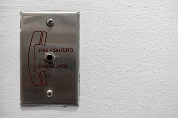 Fire fighterâ€™s phone jack panel mounted on the white wall. It meaning for carefully and be pleasure.