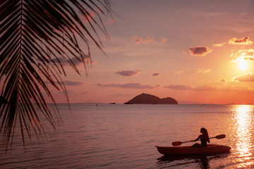 Naklejka na ściany i meble Girl on kayak sea at sunset, healthy lifestyle design. Sport, recreation Summer water sport, adventure outdoors. Tropical beach.