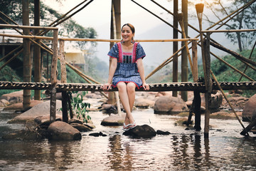asian girl in holiday by sit relaxation on bridge bamboo in nature mountain and watercourse by wearing lanna dress north thailand