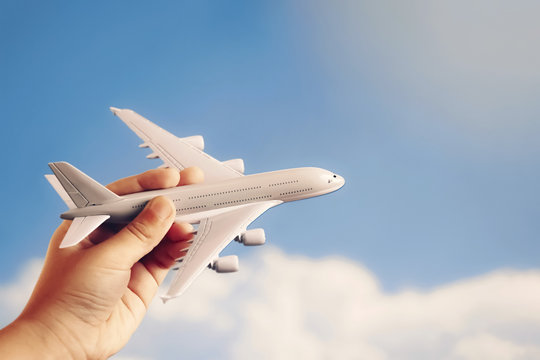 toy plane in hand of kid against blue sky