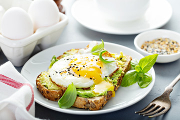 Avocado toast with fried sunny side up egg with runny yolk