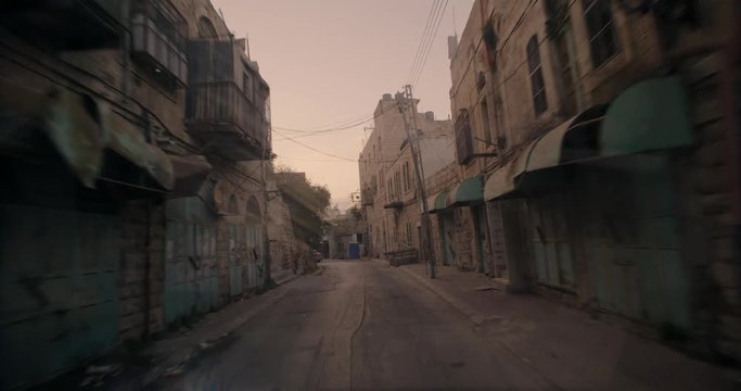 Pov of car driving in a palestinian neighborhood in hebron, israel. Sunset time.