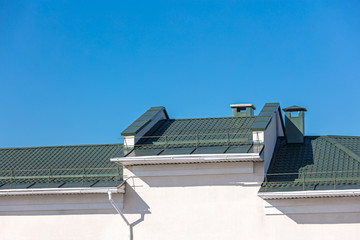 Fototapeta premium new green metal roof with drainpipe system on blue sky background