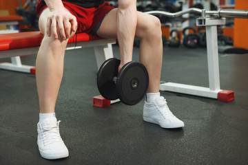 Young, athletic guy lifting dumbbells in the gym.