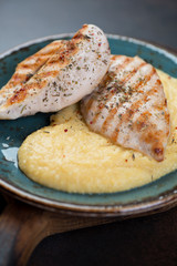 Close-up of polenta with fried chicken breast fillet, selective focus, vertical shot