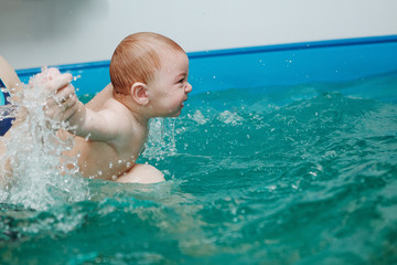 Mother with baby exercises in the pool.