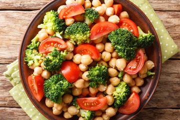 Organic vegetarian salad of broccoli, chickpeas and tomatoes with olive oil closeup on a plate. Horizontal top view