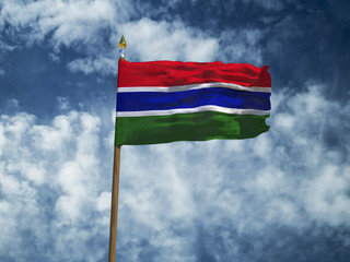 Fototapeta na wymiar Gambia flag Silk waving flag of The Gambia made transparent fabric with wooden flagpole gold spear on background sunny blue sky white smoke clouds real retro photo Countries of world 3d illustration