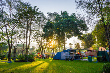 Camping and tent in nature park with sunrise - obrazy, fototapety, plakaty