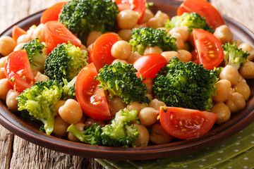 Fresh salad of broccoli, chickpeas and tomatoes seasoned with olive oil close-up on a plate. Horizontal