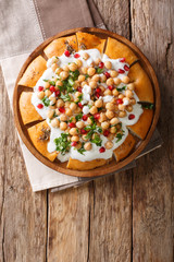 Middle Eastern pita with chickpeas, yogurt and pomegranate seeds close-up on a plate. Vertical top view