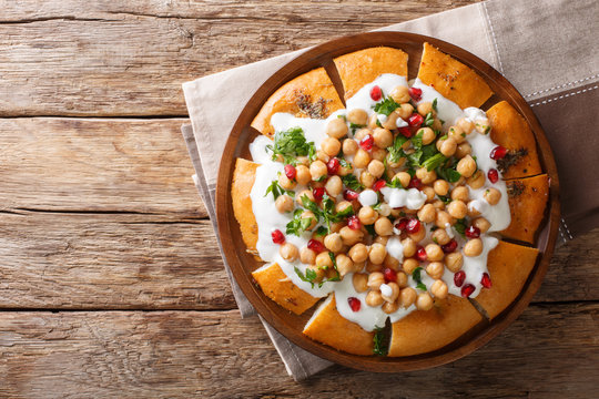 Middle Eastern pita with chickpeas, yogurt and pomegranate seeds close-up on a plate. Horizontal top view