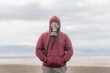 Alone man in a gas mask on a deserted field. Apocalypse postnuclear Doomsday scenario