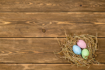 Easter eggs in a natural straw nest. Top view. Empty space for text