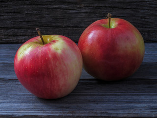 Two juicy ripe red-yellow apples on a wooden table.