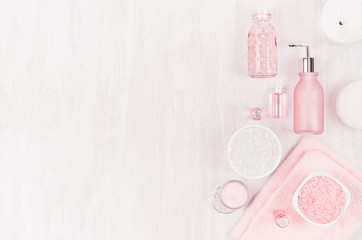Different cosmetic products and accessories in pink and silver color on soft light white wood background, copy space, top view.