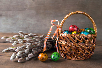 Wicker basket with Easter eggs and willow twigs bouquet