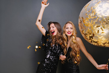 Brightfull expressions of happy emotions of two amazing girls celebrating party on black...