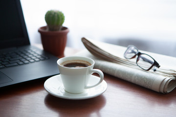 Newspaper with computer on table. Coffee break.