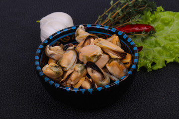 Pickled mussels in the bowl served pepper, garlic and salad