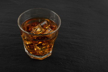 Iced Whiskey Glass on Natural Black Stone Background