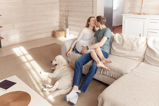 Young lovers newlyweds relaxing together on the sofa in the living room of their country house next to the dog lying on the floor during the weekend