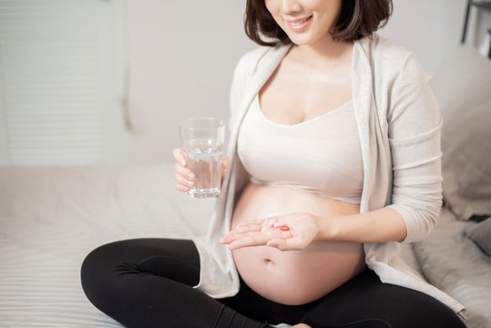 Close up pregnant woman eating vitamin pills