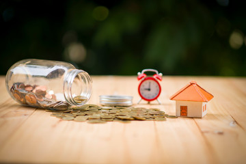 A piggy bank put on the stacking gold coins and blackboard house and clock on the vintage blue background, saving money for buy a new real estate or loan for planned investment in the future concept.
