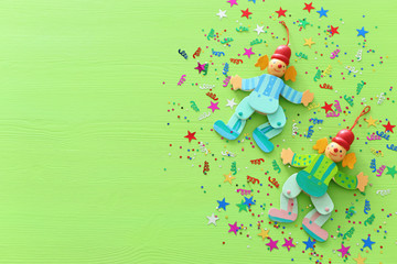 Purim celebration concept (jewish carnival holiday), clowns and confetti over wooden green...