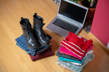 pile of second hand clothing and shoes with computer on floor