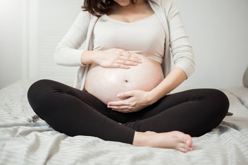 Close up of Pregnant woman applying cream at her belly