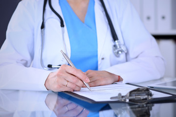 Female doctor filling up medical form on a clipboard, closeup. Healthcare, insurance and medicine concept