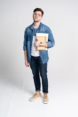 Happy young student standing full length with books and notes isolated on white background.