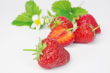 Ripe strawberries with flowers and leaves on a white background