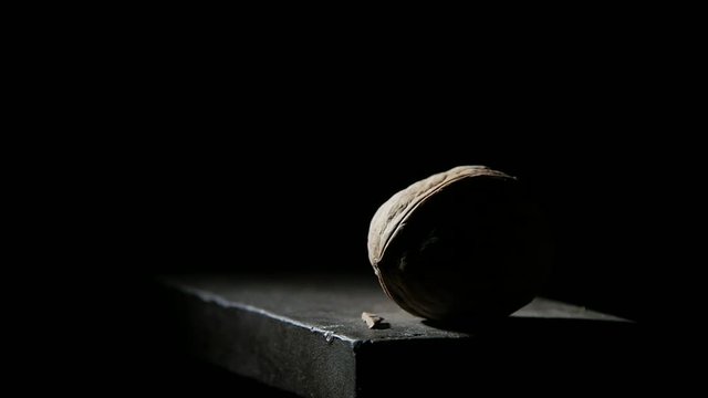 man smashes nuts with a hammer on the anvil in slow motion on black bg